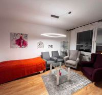 Living room in a one-room apartment with armchairs, a carpet, and a wooden decor floor.