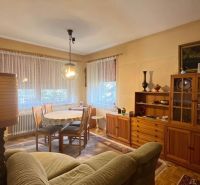 Living room in a family house with a wooden wall unit, sofa, and dining table.
