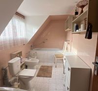 Bathroom in a family house with a bathtub, sink, toilet, and white tiles.