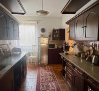 A kitchen in a family house with dark cabinets and a cozy carpet on the floor.