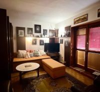 Living room with comfortable seating, decorations, and a wooden-patterned floor in a family house.