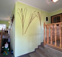 Light green hallway with wooden railing, table, and wall decoration in a family house.