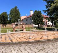 A fountain and a bench with carved figures in the village of Polomka.