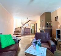 Living room in a family house with a wooden decor floor, fireplace, and staircase.