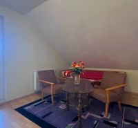 A room with armchairs and a table, a wooden-patterned floor, flowers on the table.