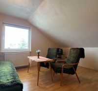 A room in a family house with a floor featuring a wooden decor, a sofa, and armchairs.