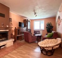 Living room with a fireplace, sofa set, and wooden decor flooring in a family house.