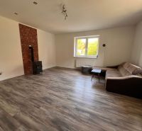 Living room in a family house with wood-patterned flooring, a fireplace, and a sofa.