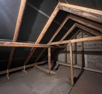 Attic space of a family house with wooden beams and unplastered walls.