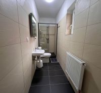 A bathroom in a family house with tiles, a sink, and a shower enclosure.