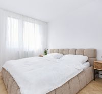 A bedroom with light walls, a bed, and a table in a 4-room apartment, with a wooden decor floor.