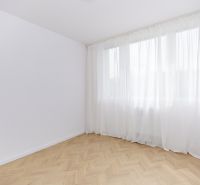 A spacious room with a wooden decor floor and white curtains in a 4-room apartment.