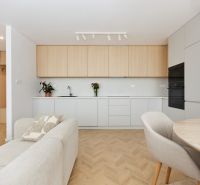 Kitchen in a 4-room apartment, white cabinets, plants, sofa, floor with wooden decor.