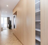 A hallway with built-in wardrobes in a 4-room apartment with a floor featuring a wooden decor.