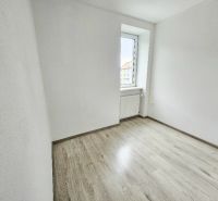 A room in a one-room apartment with a wooden decor floor and a light wall.
