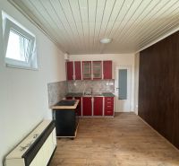 A kitchen unit with red cabinets and a wooden decor floor in a 2-room apartment.