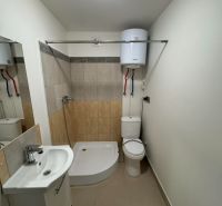 Bathroom in a 2-room apartment with a bathtub, sink, and toilet, light wall tiles.