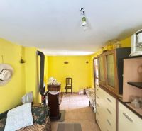 The interior of a cabin with bright yellow walls, a sofa, a wardrobe, and a stove.