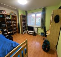 A room in a 3-room apartment with shelves, a bed, and a wooden decor floor.