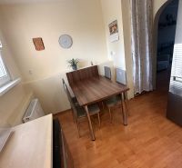Dining area with a table and chairs in a 3-room apartment with a wooden decor floor.
