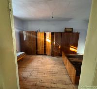 A room in a family house with wooden furniture and a bed on the floor with wooden decor.