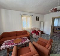 Living room in a family house with an orange sofa and a patterned carpet.
