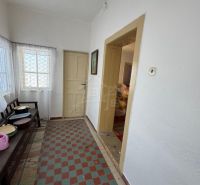 Hallway in a family house with a tiled floor, white walls, and simple furnishings.