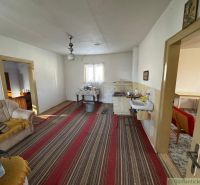 Interior of a family house with older furniture, a striped pattern carpet, and a sofa.