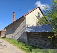 A family house in Šumiac with a metal roof, adjacent to green nature and a road.
