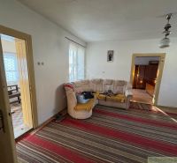 Family house with a carpet, beige sofa, doors, and a painting on the wall.