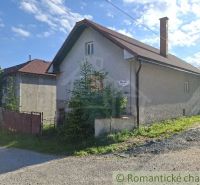 A family house in Šumiac with a metal roof and a garden by the road.