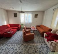 Living room in a family house with red and orange sofas and a carpet.