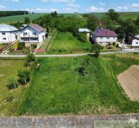 Lands - housing in Karna: green areas, houses, and an access road under the blue sky.
