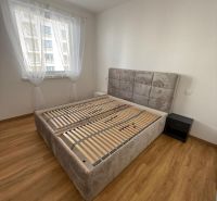 Bedroom in a two-room apartment with a wood-patterned floor and a large bed.