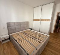 A bedroom with a bed, a wardrobe, and a wooden decor floor in a two-room apartment.
