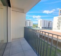 A balcony in a 2-room apartment in Poprad with a view of modern buildings and greenery.