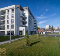 An apartment building in Poprad with a green lawn and neighboring buildings in the background.