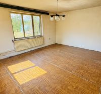 A room with a wooden floor design, a large window, and a radiator in a family house.