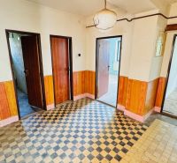 A hallway in a family house with tiled flooring and wooden decor on the walls.
