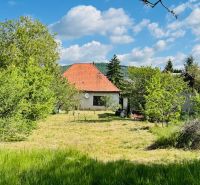 A family house in Pažiť surrounded by trees and a lawn with a red roof.