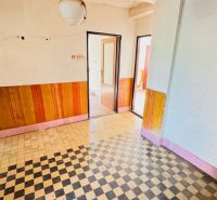 The interior of a family house with a tiled floor and wood decor on the walls.