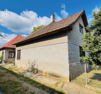 A family house in Pažiť surrounded by greenery, with a red roof and wooden windows.