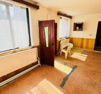 The interior of a family house with open doors, plastic chairs, and large windows.