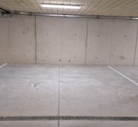 Underground garage with concrete floor and lighting.