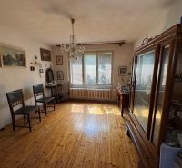 A room in a family house with wooden decor, vintage furniture, and many paintings on the walls.