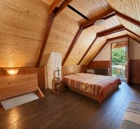 Interior of a cabin with wooden paneling and a floor with a wooden decor, visible bed and entrance.