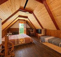 Attic room in a cottage with wooden decor and a bed.