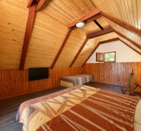 The attic in the cottage with wooden decor offers a bed and a television.