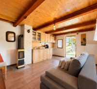 Interior of a cabin with a wooden decor floor, sofa, stove, and kitchen unit.
