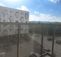 A balcony in a one-room apartment with a view of the parking lot and surrounding mountains.